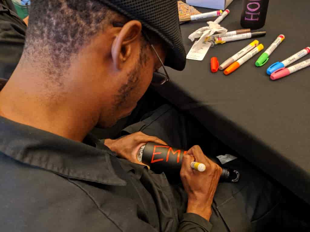 Guillermo uses paint pens to customize branded water bottles.