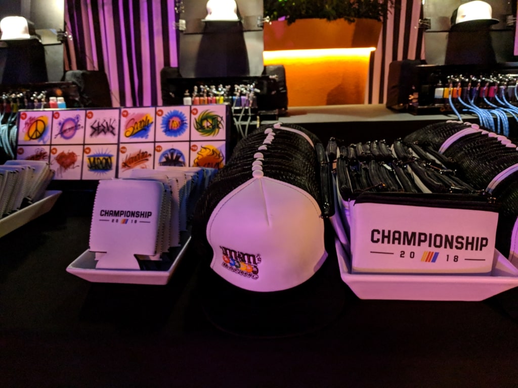 white nascar hats and koozies line up on a table ready to be airbrushed