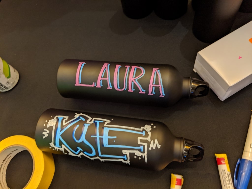 2 Black Stainless Steel Water Bottles With Names Painted With Paint Pens For Promotional Gifts