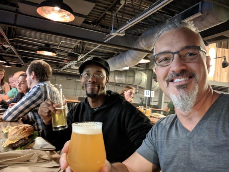 Regis and Pete sit at a bar holding beer