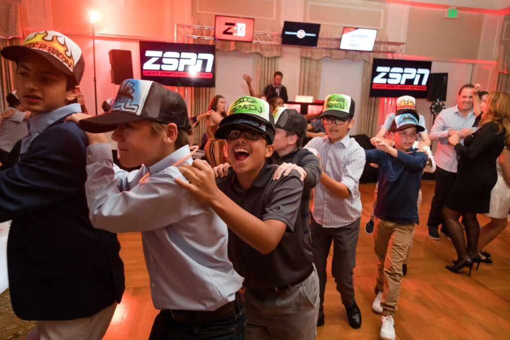 6 boys wearing airbrushed trucker caps make a human train with smiles on their faces.