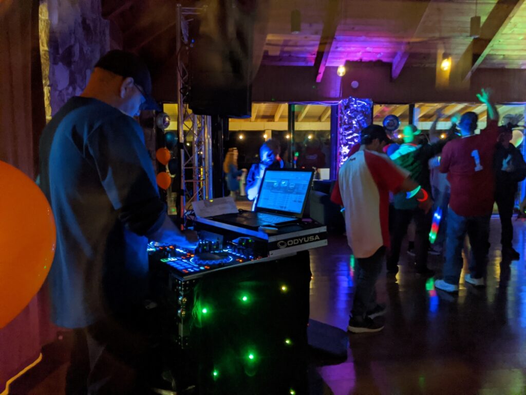 A DJ spins the tunes in front of dancing crowd of people at a bar mitzvah party.