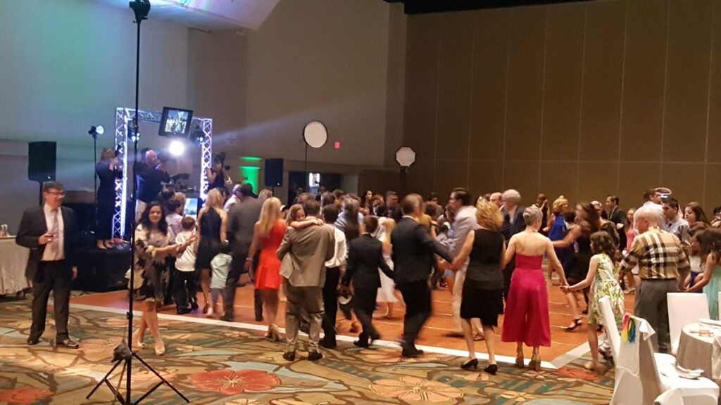 Bar Mitzvah attendees dance in front of a brightly-lit stage