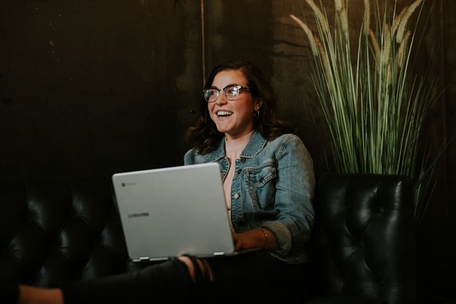 a girl with a jean jacket sits in front of a computer