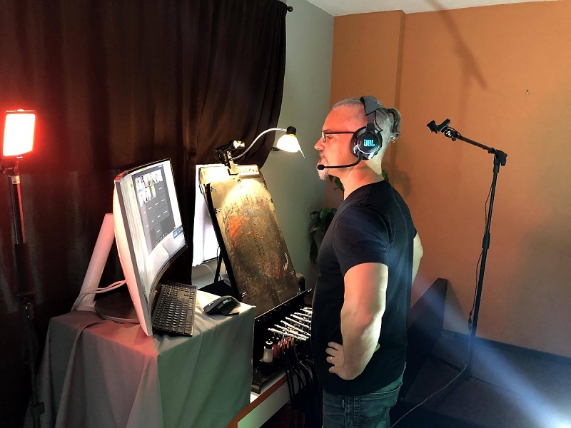 a man stands in front of computer with a headset on and hands on his hips- launching virtual airbrush events