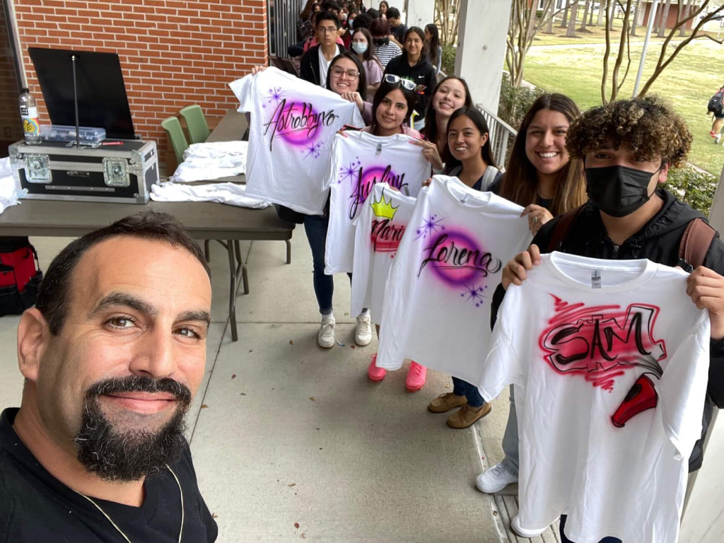 People showing off their airbrush shirts they got at a school party.